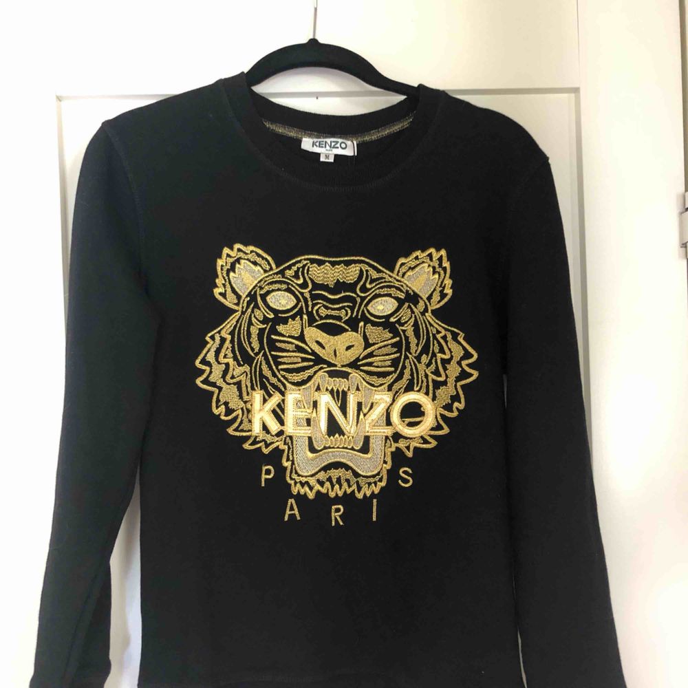 Svart långärmad tröja med guldigt Kenzo tryck. Aldrig använd! Tröjan är storlek M men väldigt liten i storleken. Hör av er för frågor!. Tröjor & Koftor.