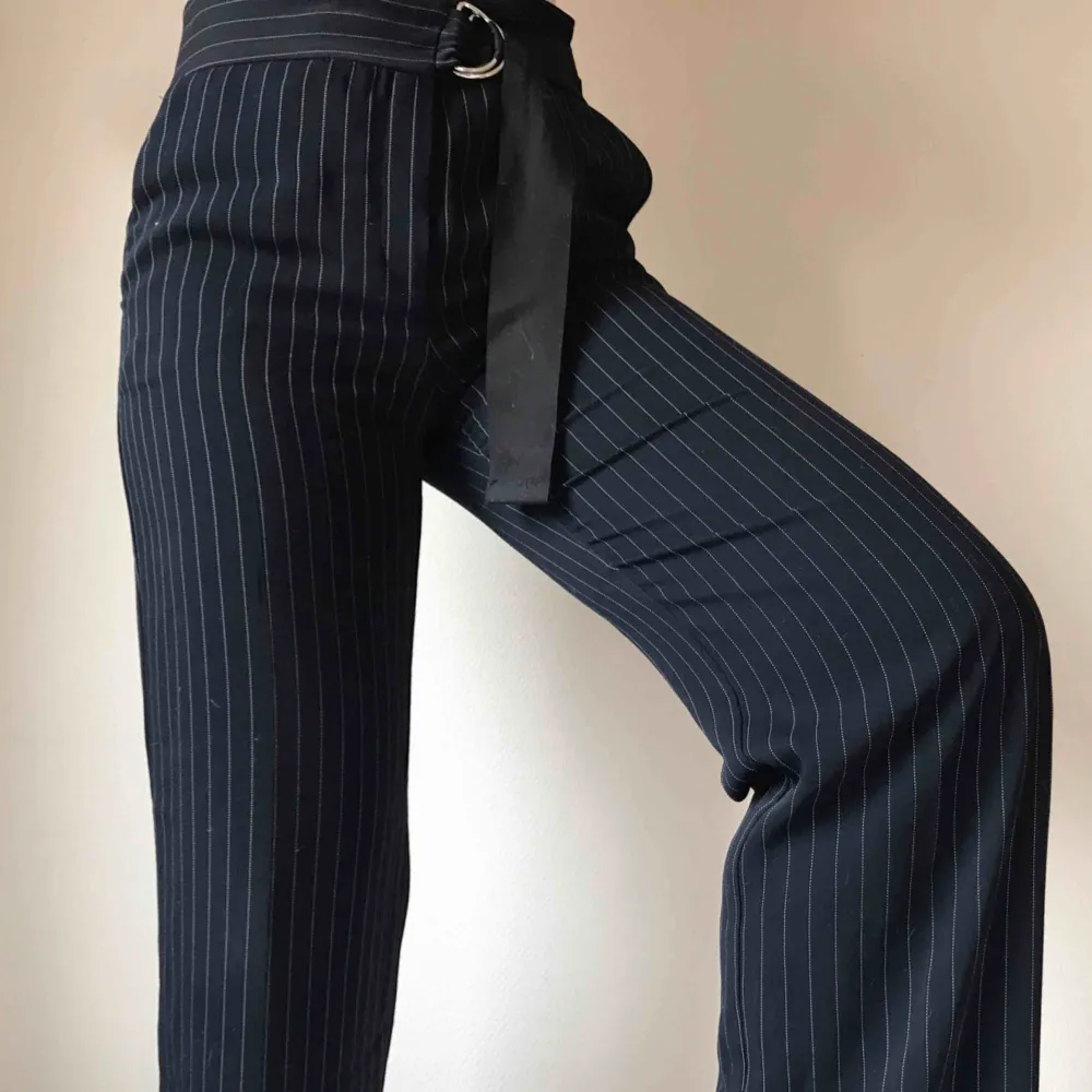 Utsvängda mörkblåa kritstrecksrandiga kostymbyxor i mjukt härligt material från Mango • stängs med dragkedja, knapp och inbyggt skärp • storlek 38 men passar 40/42 bättre • sömmen längst ned på ena benet har släppt, se bild ☁️Frakt tillkommer☁️. Jeans & Byxor.