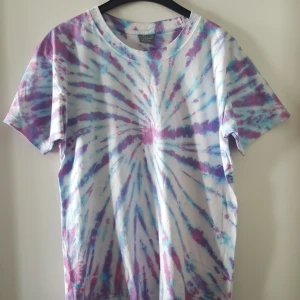  - Vintage t-shirt med batik. Storlek XL, men skulle nog mer säga den är ca som en L. Har ett pyttelitet igensytt hål nedtill bak på t-shirten (se bild 2). Kan skickas om köparen står för fraktkostnaden som blir 36kr.