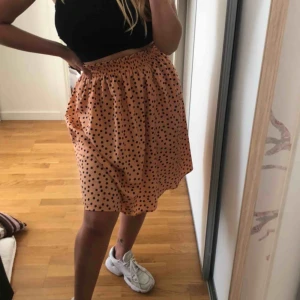  - Väldigt söt aprikosfärgad kjol med marinblå prickar, går ner till knäna för mig som e 164, köpt i Danmark 