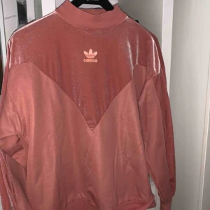  - Rosa tjocktröja från Adidas i blandat material, med halv-polo krage. Jättefin och skön!! Tror det är storlek S men kan passa allt mellan XS och M beroende på önskad passform. Säljer pga använder inte så mycket längre.   !! Frakt ingår ej !!