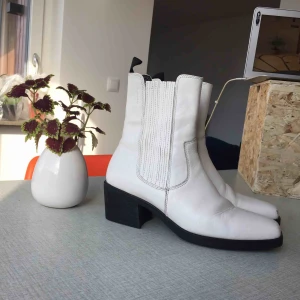  - Vita cowboybooten ”Simone”, med trubbig tå. Suuupersköna att gå i! Bruksslitage på skinnet, men generellt fint skick och hel sula. 