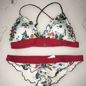 Blommig bikini - Bikini i fint skick då den endast är använd en gång och tvättad! Korsande band på ryggen och lite volangmodell. Underdelen i strl. 36 och överdelen i 38 men då både banden över axlarna och runt midjan är justerbara passar den även en 36:a ev en 34:a❤️