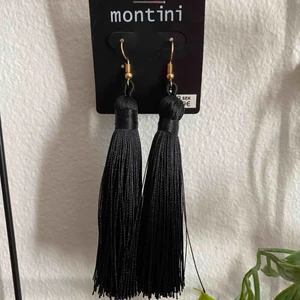  - Ett par örhängen med svarta tofsar och guld detaljer.  Aldrig använda.  