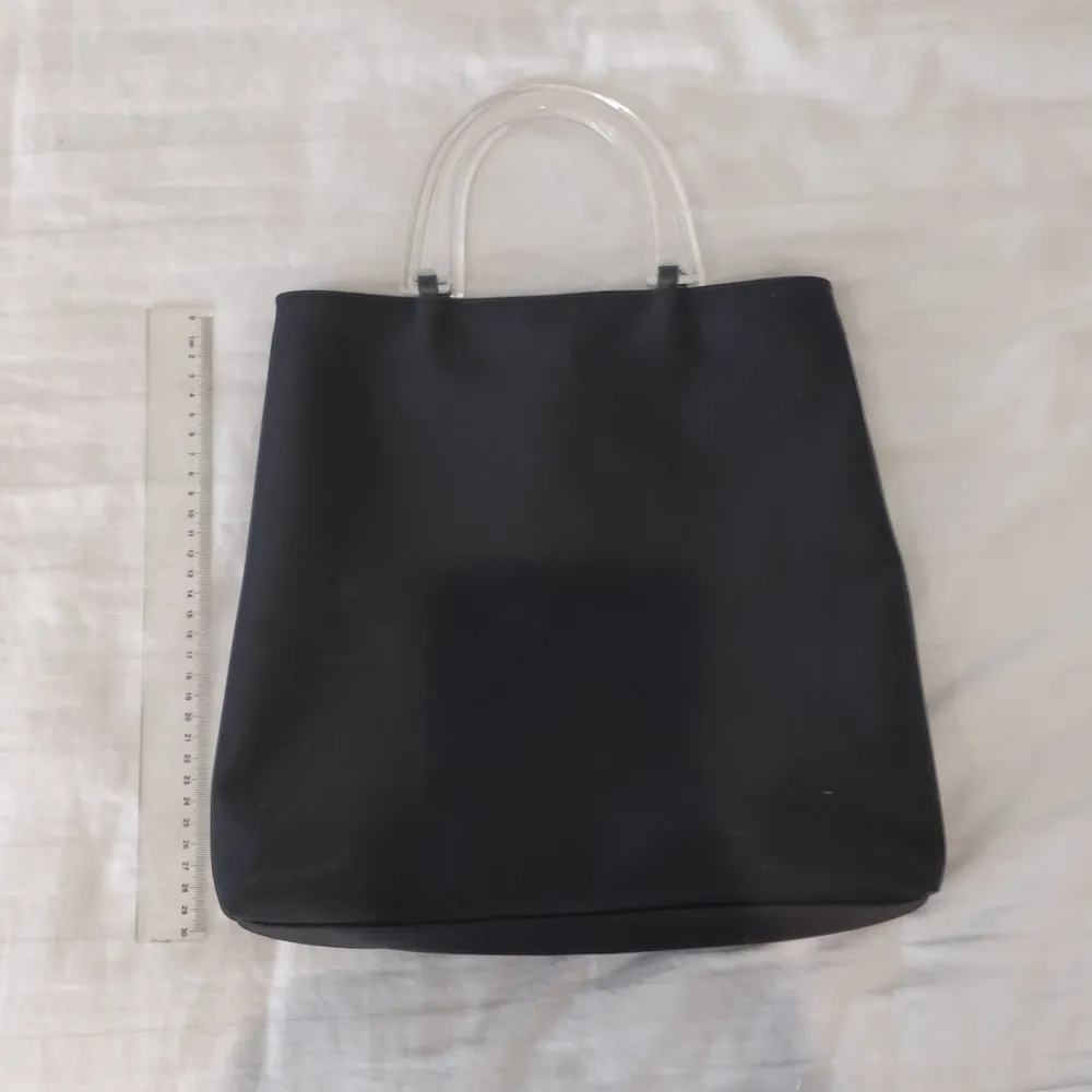 Y2k svart handväska med genomskinliga handtag. Köptes på secondhand och kommer tyvärr inte till användning. Jättebra skick. (Frakt ingår) . Väskor.