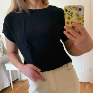  - Svart t-shirt i ett ”blusmaterial”, dragkedja baktill. Väl använd med i fint skick. 