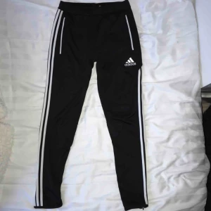  - Adidas byxor med 3 sträck på sidan av benen och dragkedja vid benslut. 