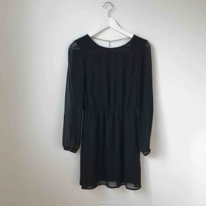  - Svart festklänning med öppen rygg och guldkedja.  I fint skick. Köparen står för fraktkostnad enligt postens portotabell.