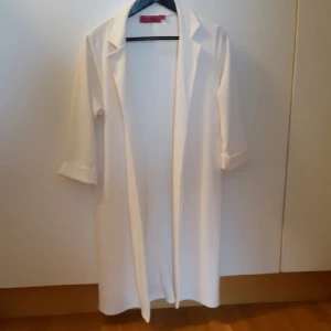  - Vit lång kofta/jacka med uppvikta armar i strl 40. Möts gärna i Gbg, annars tillkommer fraktkostnad för köparen. 