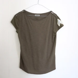  - T-shirt från hunkydory! Nypris 900kr.
Snygg armylook med den lilla detaljen på ärmen.
Använd endast en gång så i nyskick! 
Material 67% lyocell 33% cotton. 
Frakt 35kr! Jag har svisch. 