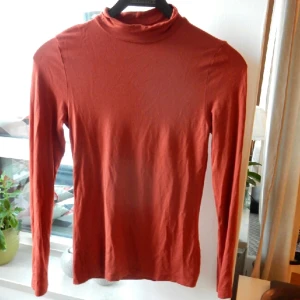  - Snygg halvpolo från ginatricot. Bronsröd till färgen, lite liten i storleken och använd ett fåtal gånger. Fint skick! 