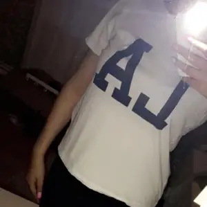 En vanlig vit T-shirt som det står LA på med blåa bokstäver.
