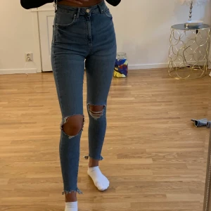 Jeans med slitningar  - Ett par ass snygga högmidjade jeans med slitningar från Gina Tricot som tyvärr inte kommer till användning längre, byxorna passa xs/s, nypris på ca 600kr 