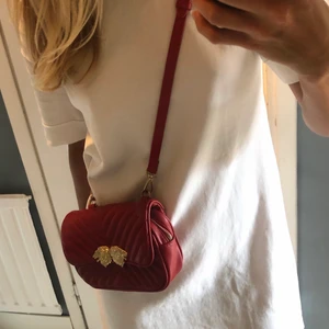 Väska - Väska i röd läderimmitation från Zara. Går att använda både som magväska och axelremsväska då det följer med remmar till båda alternativen. Mycket dekorativ och ger det lilla extra till en outfit. Köper står för eventuell frakt.