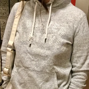 Grå vit enkel hoodie🤍✨ - En grå vit HM hoodie där det står ✨” forever whatever” ✨ I bra skick förutom ena snöret som är lite slitet. Säljer på grund av rensning! Frakt tillkommer!