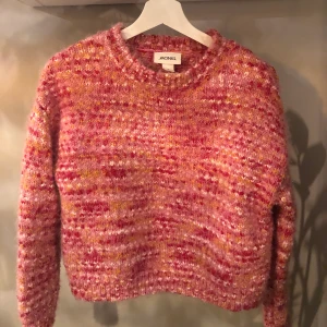 Monki stickad tröja strl M - Stickad, ganska boxig tröja från Monki. Rosa med detaljer i röd, orange och vit. Något glansig. 