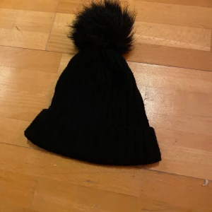 Svart mössa med knopp - En svart mössa med en fluffig knopp, super fin! Men säljs för den inte kommer till användning, använd kanske 1 eller 2 gånger. Super fin, mysig och håller värmen. 30kr + frakt 📦 