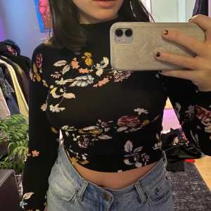 Polotröja - En svart polotröja med blommigt mönster på. Den är verkligen så så mjuk och sitter fint på! Den är stretchig och endast använd 1-2 ggr✨