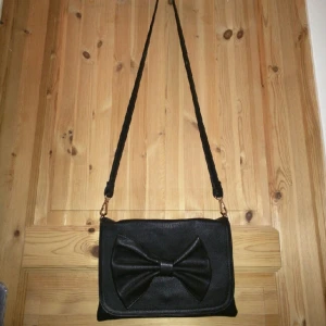  - En mindre väska med rosett, köpt i Italien. Läderimitation Bra med mindre fack inuti Knappt använd nypris 400:- (Rosetten kan se skev ut på bild, detta går att justera)