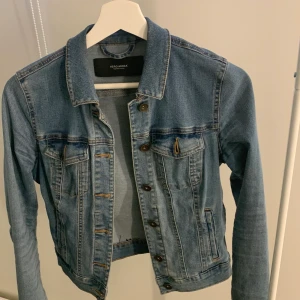 Blå jeansjacka storlek XS - Denna blå jeansjacka är i bra skick. Har använts ett par gånger. Slutat använda eftersom den har blivit för liten i storleken för mig.