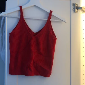 Rött linne i snyggt material - Skönt rött linne som är randigt i materialet. Passar jättebra till många olika saker(svarta/blåa jeans, svart kjol etc). Den är XS men materialet är så stretchigt att de passar mig som är M UTAN att det är tajt i det minsta. Hör av dig för fler bilder!