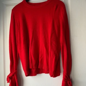 Röd tjocktröja  - En röd stickad tjocktröja från NaKd. Har rosetter längst ner vid armarna. Är lite oversized vilket är väldigt skönt.✨