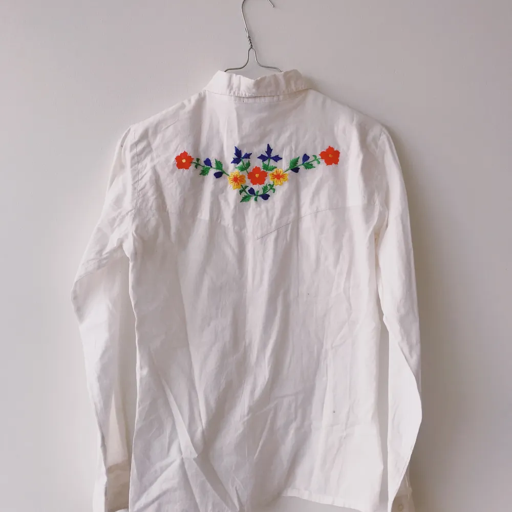 Superfin skjorta i 100% bomull med blom-brodyr på bröst och bak. Inköpt i liten butik i Italien men har tyvärr aldrig kommit till användning. . Skjortor.