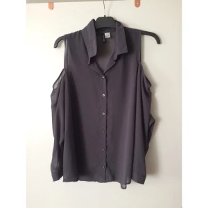  - En grå transparent tröja med öppna axlar. 
Normal i storlek.