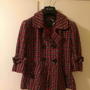  - Snygg figursydd hallonfärgad rutig kavaj i jättebra skick. Ovanlig färg och modell, trekvartsärmar med spänne som går att variera. Knapp upptill går att knäppa el ha uppvikt, se foton. Skjorta, t-shirt alt  tröja passar ha inunder. FRAKTFRITT.