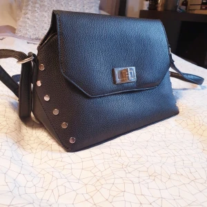  - Triangulär väska från Boohoo.  Ca 30 cm bred och 15 cm hög. Botten är ca 13x30 cm Man får plats med massor, enda anledningen till att den säljs är för att jag äger 35 andra svarta väskor.  Självklart fakeläder! Skickas (max 37kr frakt) eller möts i Göteborg.