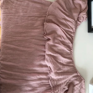 Söt rosa topp med volang! - Jättefin och skön topp från Nelly! Nytt skick! Man kan använda den som både off shoulder topp och ha den på axlarna som vanligt!