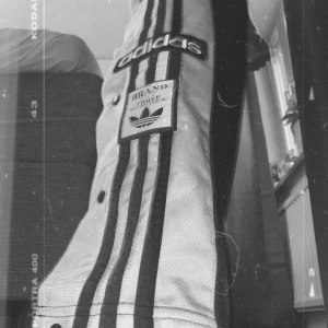 Adidas popper pant - Adidas trendiga byxor med knappar på sidorna, lite slitna på knäna(kan skicka bild om så viljas)🦋