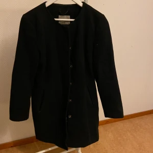 Svart kappa från Vero Moda - Storlek L. Fint skick utöver ett hål i fodret i en ficka. Går lätt att sy ihop.