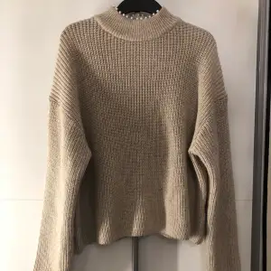 En beige stickad tröja från H&M med pärlor på kragen, storlek S. Använd endast en gång och har inga fel. 