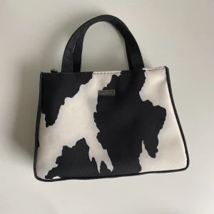 Ko mönstrad väska - En ko mönstrad miniväska köpt här på Plick av en tjej som inte berättade att den hade fläckar, har inte testat att ta fläckborttagning så det kan funka, tänkte mer att det var synd att slänga den✨