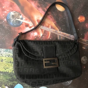 Fendi zucchino mama baguette - Zucchino-monogram. Magnetiskt spänne, axelrem, flera innerfickor, man kan ha den på två sätt med flärpen inåt eller utåt (se bild 1 & 2) Djup: 4 cm Höjd: 15,5 cm Bredd: 25 cm. Tillverkad i Italien och köpt och autentiserad på Vestiaire Collective. Skriv gärna för fler bilder. Annonsen finns på fler sidor. 😊