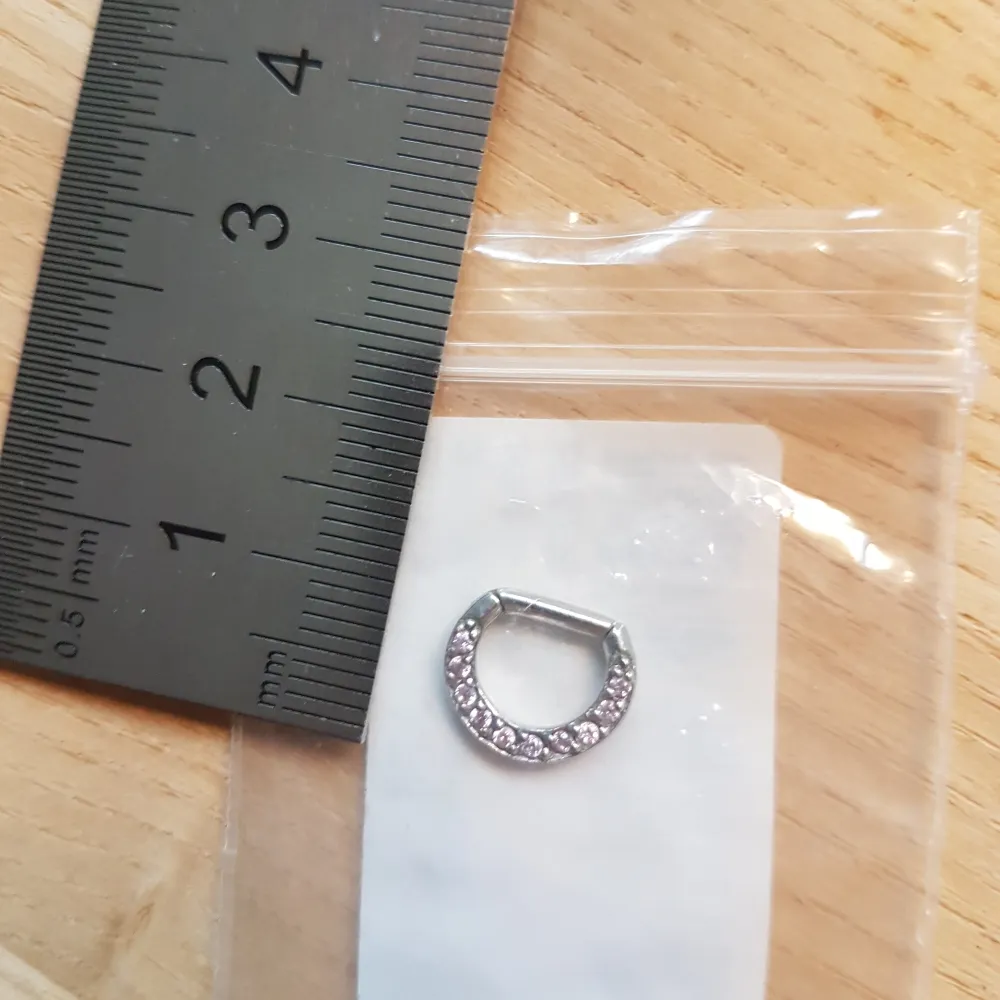 Säljer en oanvänd Septum piercing med clicker. Ca 1 cm lång. Piercingen ser ut som denna på bilden, men har ljusrosa stenar. . Accessoarer.