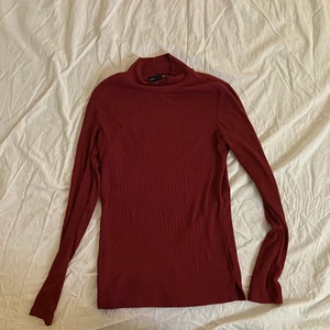 Ribbad, långärmad, vinröd turtleneck - Vinröd långärmad turtleneck/polotröja i ribbat och hyfsat tunt material. Kommer från Lager 157. Storleken säger S men skulle säga att den mer är XS. 