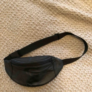  - Fannypack i svart läder. Ett stort fack och ett fack på baksidan, justerbar axelrem. Möts upp i Sthlm eller skickar mot fraktkostnad. 