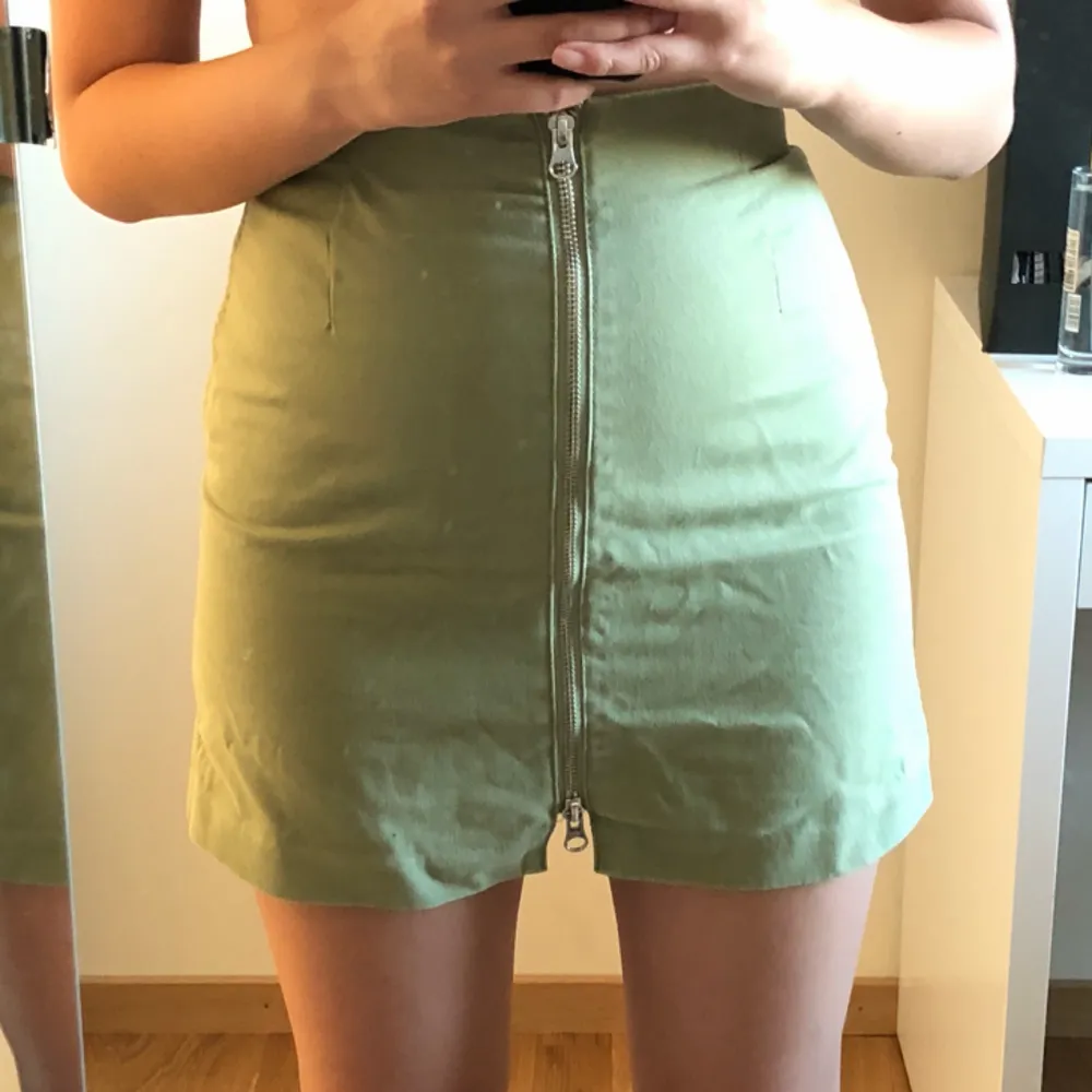 Grön kort kjol från Weekday, säljes pga för liten. Midjemått 64cm. Färgen stämmer bäst överens med sista bilden. Använd men inte sliten. Frakt inkluderad.. Kjolar.