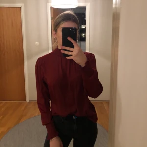 Vinröd blus - Jättefin vinröd blus med resår polo samt resår vi slutet av ärmen. Även en liten öppning vid ryggen. Knappt använd och är i mycket bra skick. Frakt ingår i priset.