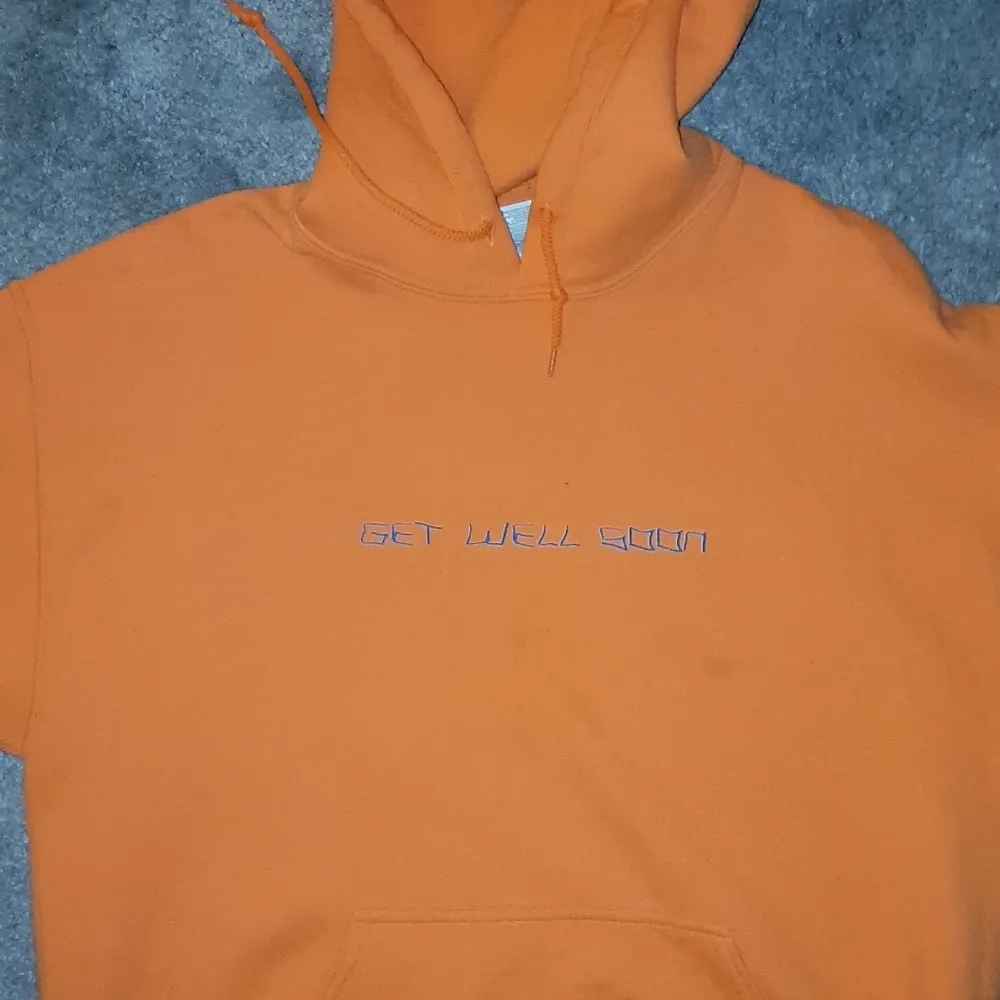 En orange hoodie från artisten, loveonfriday. Framsidan står det 