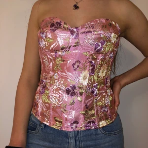 Rosa korsett topp - En rosa korsett topp med blom mönster. Storlek UK 8/S. Den är från prettylittlething och har en dragkedja där bak. Oanvänd, prislapparna sitter kvar, bäldigt bra kvalité