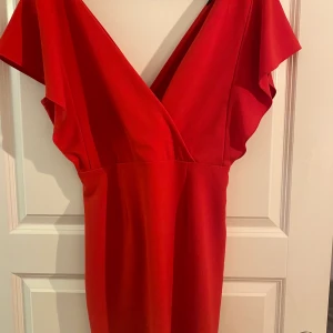 Röd Klänning - Riktigt snygg klänning som tyvärr aldrig kommit till användning! Aldrig använd så nyskick! Dragkedja på ena sidan! FRAKT INGÅR