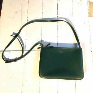  - Céline trio bag i mörkgrön färg med guldiga detaljer i äkta skinn! Använt skick Inget äkthetsintyg! Frakt tillkommer annars finns det möjlighet till avhämtning! P.s jag står inte för postens eventuella slarver!