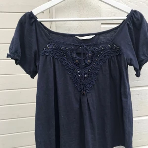  - Marinblå odd Molly blus i storlek S med fina detaljer vid bröstet. Kan användas som både off shoulder blus och blus med täckande axlar. Ej använd! Frakt: betalas själv om ingen annan överenskommelse eller plan för mötesplats.