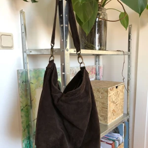  - Mörkbrun väska i äkta mocka. Påsmodell. Handtaget går att ta av så du kan byta ut till lägre eller kortare.   Hämtas på Gärdet. Kan gå ner i pris vid snabb affär :) 