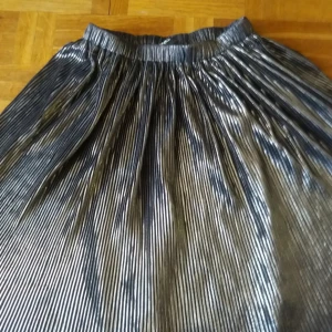  - Veckan kjol med fin silverglans. Elastisk midja. Frakt: 36kr.