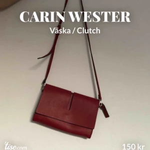  - Den lilla röda! Söt väska/clutch från Carin Wester, inköpt på Åhlens. Axelbandet är avtagbart och justerbart på samma sätt som ett skärp. Väskan besitter flera minifack, med och utan dragkedja. Stängs med dragkedja samt magnetknapp. Perfekt storlek! 