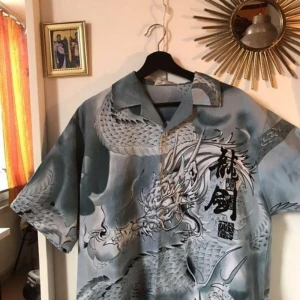  - En riktigt snygg skjorta med drake och massa annat på. Köpt på beyond retro. Endast använd några gånger så väldigt bra skick. Baksidan är identisk till framsidan!